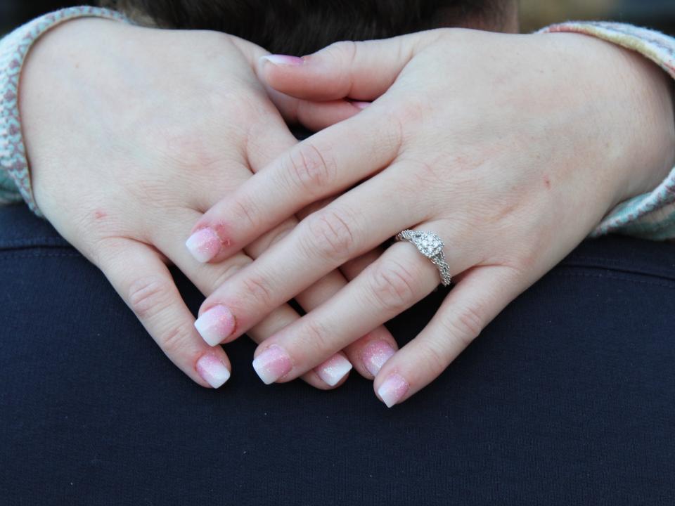Two hands with a soft-pink manicure and a wedding ring on ring finger