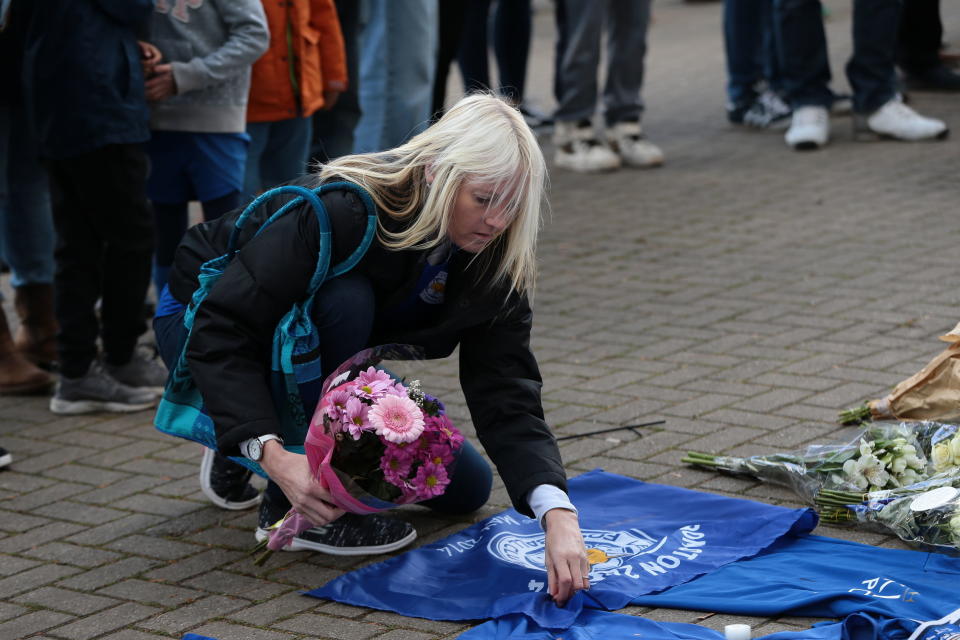 A woman places flowers outside Leicester City Football Club after a helicopter crashed in flames the day before, in Leicester, England, Sunday, Oct. 28, 2018. A helicopter belonging to Leicester City's owner, Thai billionaire Vichai Srivaddhanaprabha, crashed in flames in a car park next to the soccer club's stadium shortly after it took off from the field following a Premier League game on Saturday night. (Aaron Chown/PA via AP)