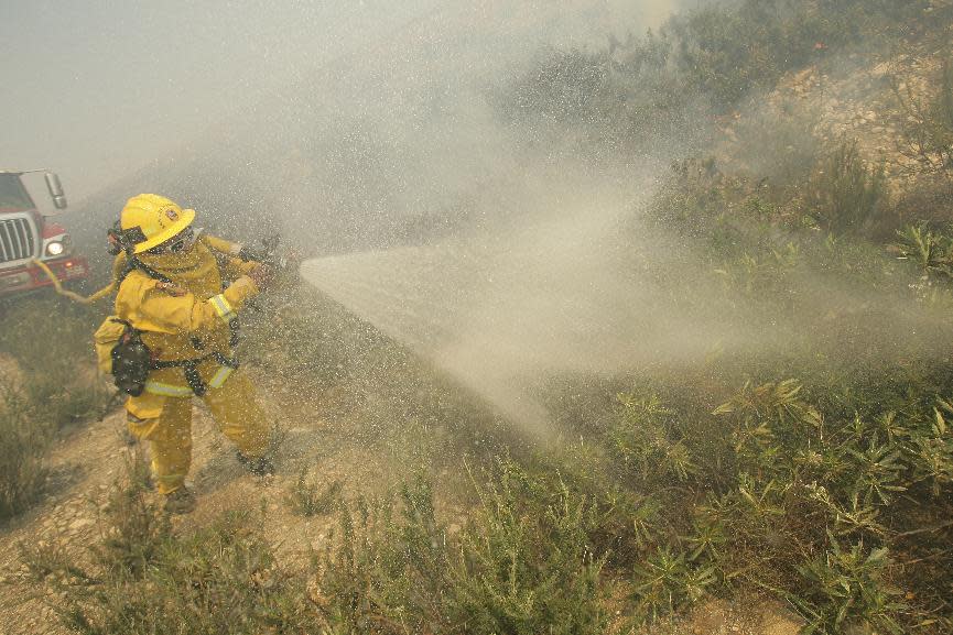 A firefighter sprays down brush as he battles a fire burning in Day Creek near the Etiwanda Preserve in Rancho Cucamonga, Calif., on Wednesday, April 30, 2014. Fire officials say winds gusting to 60 mph are pushing the flames through the foothills of the San Bernardino Mountains east of Los Angeles, although no homes are in immediate danger. Several neighborhoods and at least seven schools in Rancho Cucamonga have been evacuated. There’s no word on what sparked the blaze but it comes in the midst of a heat wave that’s created extreme fire danger. (AP Photo/The Press-Enterprise, Stan Lim) MAGS OUT; MANDATORY CREDIT