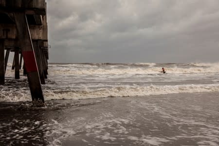 A man struggles to get through the high tide to surf after Hurricane Dorian passed the Florida coastline in Jacksonville