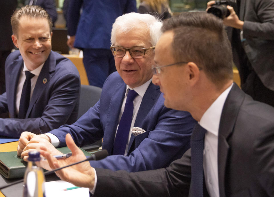Polish Foreign Minister Jacek Czaputowicz, center, speaks with Hungarian Foreign Minister Peter Szijjarto, right, during a meeting of EU foreign ministers at the Europa building in Brussels, Monday, Dec. 9, 2019. European Union foreign ministers are debating how to respond to a controversial deal between Turkey and Libya that could give Ankara access to a contested economic zone across the Mediterranean Sea. (AP Photo/Virginia Mayo)