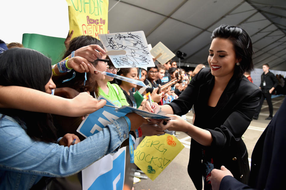Demi Lovato signs photos for fans.<p>Photo: Mike Windle/Getty Images for WE Day</p>
