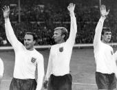 FILE - England's captain Bobby Moore, centre, is flanked by team mate George Cohen, left, and Geoff Hurst as they wave to the crowd at the end of the Football World Cup semi-final match at Wembley, London, on July 26, 1966. George Cohen, the right-back for England World Cup-winning team of 1966, has died aged 83, his former club Fulham have announced on Friday, Dec. 23, 2022. (AP Photo/Bippa, File)