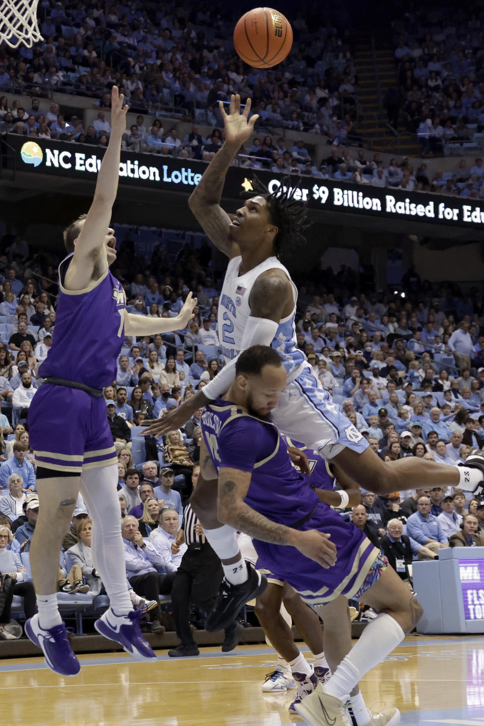 North Carolina guard Caleb Love (2) drives against James Madison guard Noah Freidel, left, and James Madison guard Takal Molson, bottom, during the first half of an NCAA college basketball game Sunday, Nov. 20, 2022, in Chapel Hill, N.C. Love was called for a foul on the play. (AP Photo/Chris Seward)