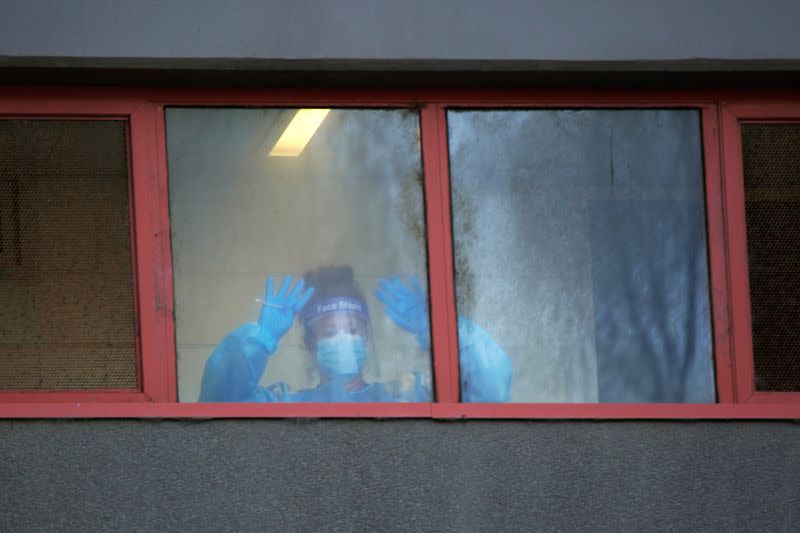 A healthcare worker signals to her colleagues from a window of a public housing tower locked down in response to an outbreak of COVID-19 in Melbourne