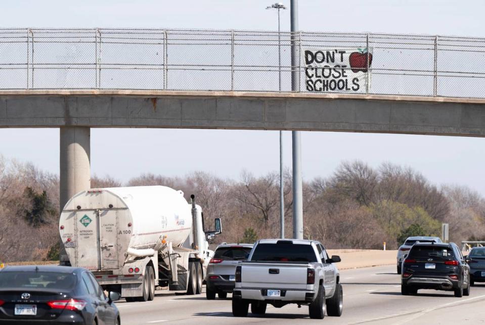 A sign that reads “Don’t Close Schools” hangs from the pedestrian walkway on Kellogg near Hillside before Monday night’s vote. Jaime Green/The Wichita Eagle