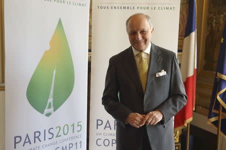 French Foreign Affairs Minister Laurent Fabius poses in front of the Paris 2015 climate change conference logo in his office in Paris, France, May 22, 2015, after an interview with Reuters. REUTERS/Philippe Wojazer