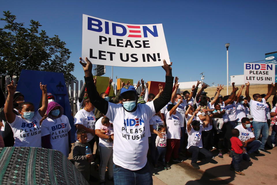 Migrants from Central America and elsewhere, hoping to cross the border and request asylum in the U.S., hold banners and shout slogans to President  Biden at their campsite outside the El Chaparral border crossing, in Tijuana, Mexico on February 27, 2021. (Jorge Duenes/Reuters)