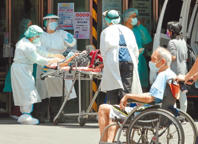 台灣疫情緊繃，指揮中心初步分析，新冠肺炎死亡年齡層大於60歲者占89.1％，平均年齡72歲。圖為1位坐輪椅的長者行經台北市聯醫忠孝院區的急診處外時，醫護人員正忙著收治1名患者。（粘耿豪攝）