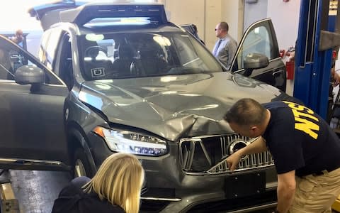 Investigators inspect the crashed Uber after the accident - Credit: Reuters