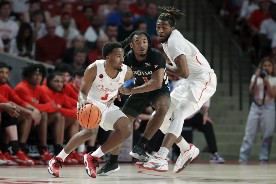 Houston guard L.J. Cryer, left, drives around Cincinnati guard Day Day Thomas, center, as Houston forward Ja'Vier Francis sets a screen during the first half of an NCAA college basketball game Tuesday, Feb. 27, 2024, in Houston. (AP Photo/Michael Wyke)