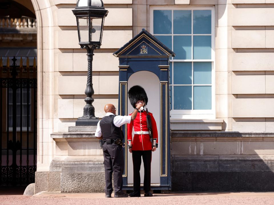 A member of the Queen's Guard receives water to drink during the hot weather in London.