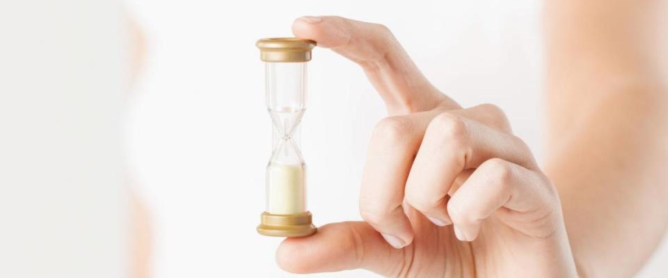 close up of woman hand holding hourglass.