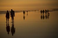 <p>Menschen spazieren im Sonnenuntergang am Strand des südspanischen Cadiz. (Bild: AP Photo/Emilio Morenatti) </p>