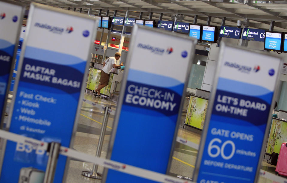 FILE - In this Tuesday, March 18, 2014 photo, a man checks in at a Malaysia Airlines counter at Kuala Lumpur International Airport in Sepang, Malaysia. (AP Photo/Lai Seng Sin, File )