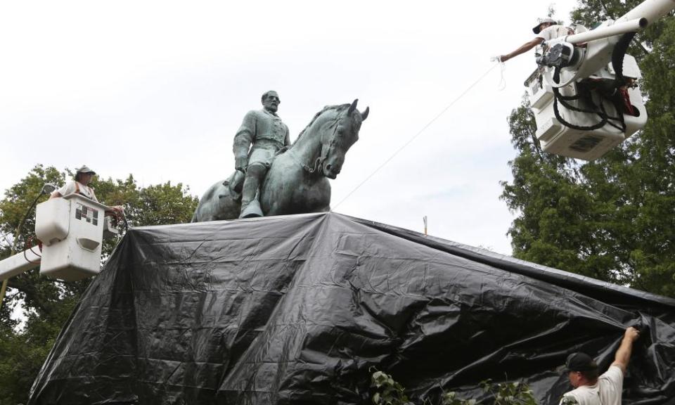 City workers drape a tarp over the statue of Robert E Lee in Emancipation park in Charlottesville, Virginia.