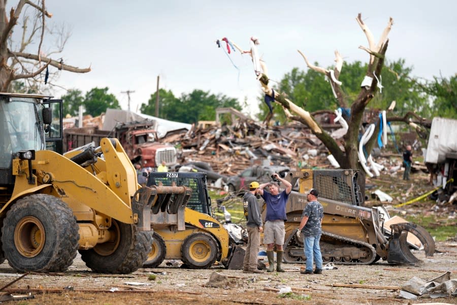 Workers stand near a home destroyed by a tornado Tuesday, May 21, 2024, in Greenfield, Iowa. (AP Photo/Charlie Neibergall)