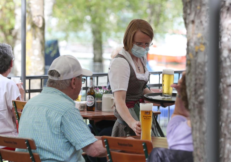 A waitress serves beer at a beer garden on May 10, the first day that outdoor restaurant seating reopened in some regions across Bavaria in Woerthsee, Germany.  (Photo by Alexandra Beier/Getty Images)