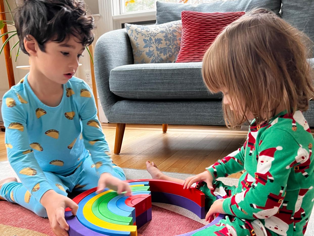 Conz Preti's children playing with a wooden rainbow.