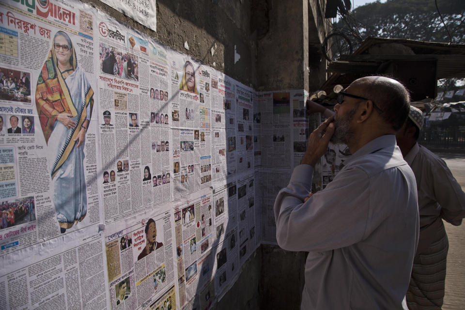 Bangladeshis read newspapers pasted on a wall in Dhaka, Bangladesh, Monday, Dec. 31, 2018. Bangladesh's ruling alliance won virtually every parliamentary seat in the country's general election, according to official results released Monday, giving Prime Minister Sheikh Hasina a third straight term despite allegations of intimidation and the opposition disputing the outcome. (AP Photo/Anupam Nath)