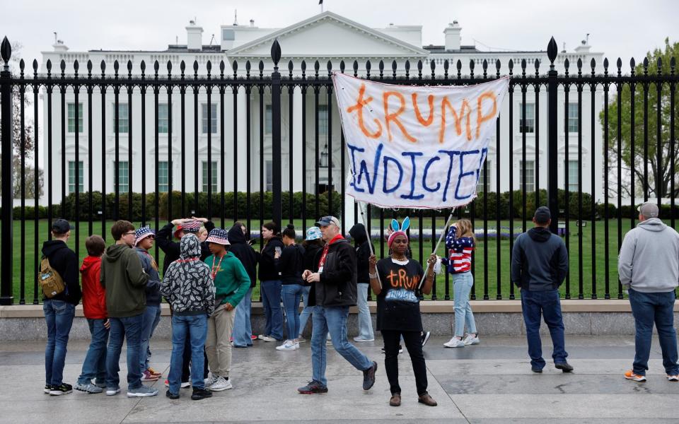 Nadine Seiler holds a "Trump Indicted" sign while students and tourist groups take pictures next to the White House - REUTERS/Jonathan Ernst