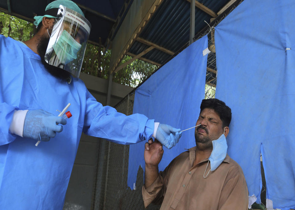 A man reacts while having a nasal swab sample taken at a testing and screening facility for the coronavirus, in a hospital in Karachi, Pakistan, Friday, Aug. 21, 2020. (AP Photo/Fareed Khan)