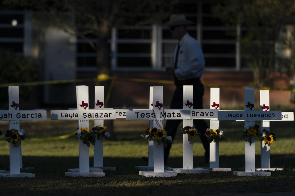 A law enforcement personnel walks past crosses bearing the names of Tuesday's shooting victims at Robb Elementary School in Uvalde, Texas, Thursday, May 26, 2022. (AP Photo/Jae C. Hong)