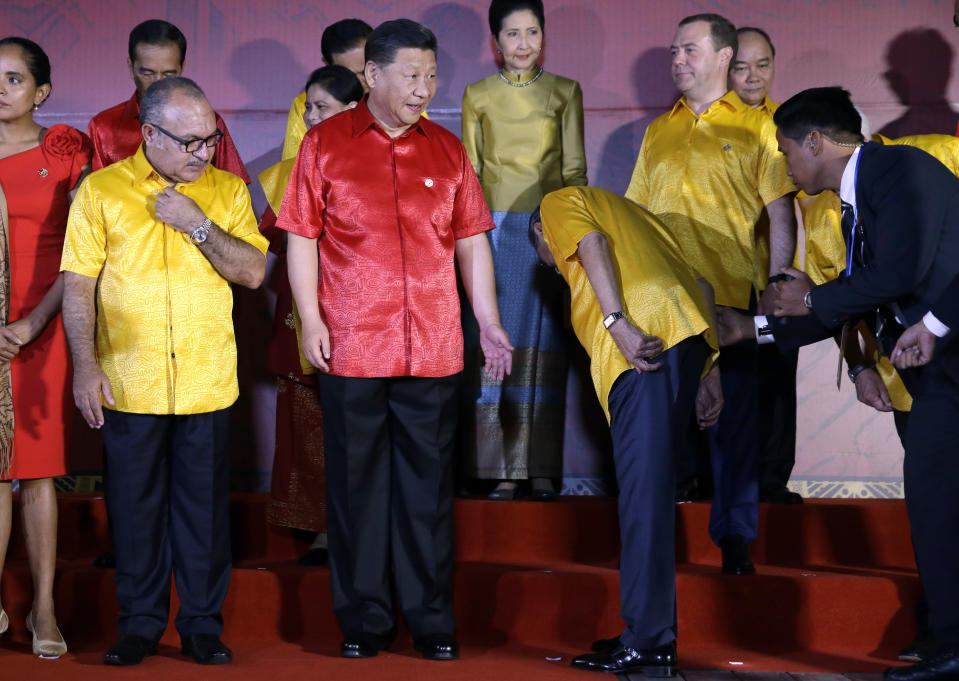 Papua New Guinea's Prime Minister Peter O'Neill, left, and Chinese President Xi Jinping watch as Malaysian Prime Minister Mahathir Mohamad looks for his spot at a family photo with leaders and their spouses during the APEC Economic Leaders Meeting summit in Port Moresby, Papua New Guinea, Saturday, Nov. 17, 2018. (AP Photo/Mark Schiefelbein)