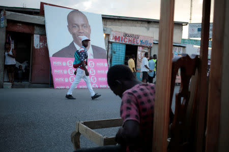 A man walks next to a billboard of presidential candidate Jovenel Moise of PHTK (Bald Head Haitian Party) ahead of the presidential election, in a street of Port-au-Prince, Haiti, November 17, 2016. REUTERS/Andres Martinez Casares