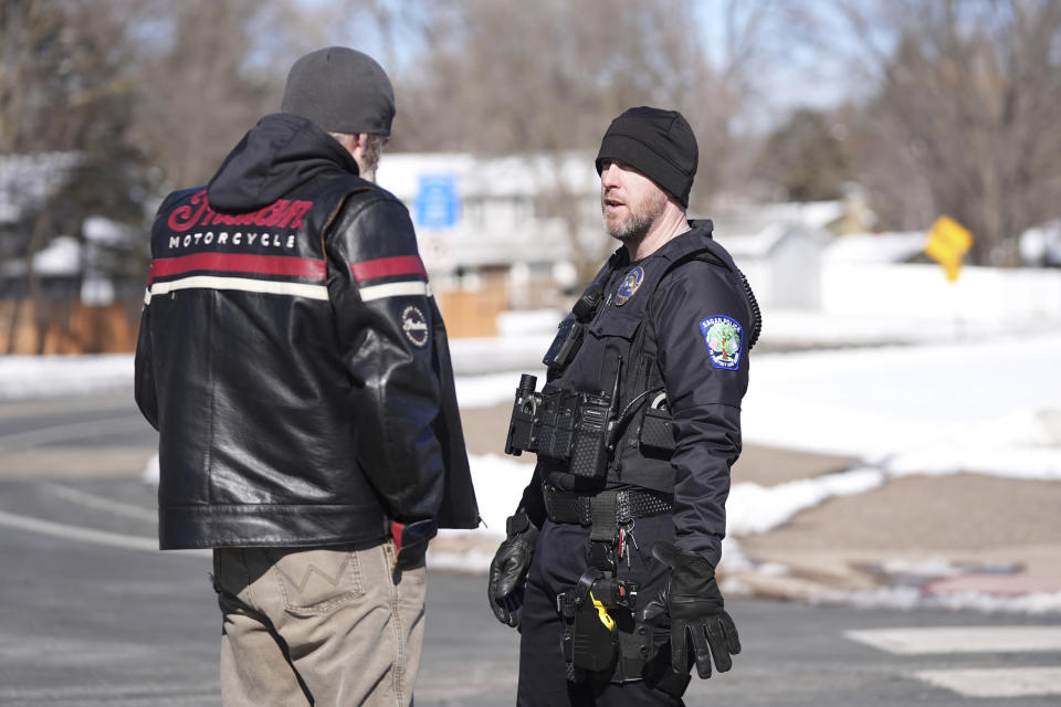 A police officer speaks to a man near the scene where two police officers and a first responder were shot and killed Sunday, Feb. 18, 2024, in Burnsville, Minn. (AP Photo/Abbie Parr)