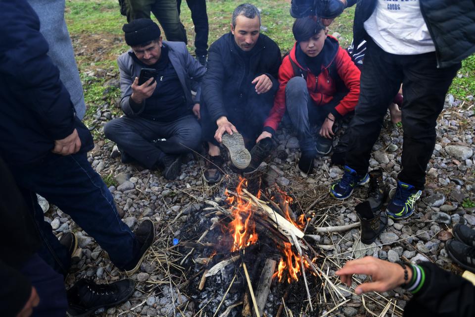 Migrants try to warm themselves around bonfire at the village of Skala Sikaminias, on the Greek island of Lesbos, after crossing on a dinghy the Aegean sea from Turkey, Sunday, March 1, 2020. Turkey's President Recep Tayyip Erdogan said his country's borders with Europe were open Saturday, making good on a longstanding threat to let refugees into the continent as thousands of migrants gathered at the frontier with Greece. (AP Photo/Michael Varaklas)