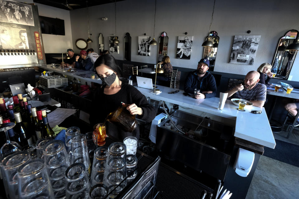 Waitress Penny Thompson prepares drinks as patrons dine at Notorious Burgers restaurant in Carlsbad, Calif., on Friday, Dec. 18, 2020. (AP Photo/Ringo H.W. Chiu)