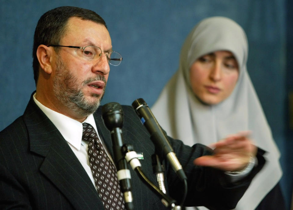 FILE - In this Feb. 16, 2004 file photo, Abdelhaleem Ashqar, left, with his wife Asma, right, meets reporters at the National Press Club in Washington, to announce his presidential candidacy for the Palestinian National Authority. Ashquar who says he fears torture at the hands of Israeli authorities, is back in the U.S. after a judge's order forced immigration authorities to reverse his deportation and bring him back from Israel before he ever got off the plane. According to court papers and interviews, U.S. authorities arrested and deported Ashqar Tuesday, June 4, 2019 after misleading him about his need to report to an immigration office to process paperwork. (AP Photo/Pablo Martinez Monsivais, File)