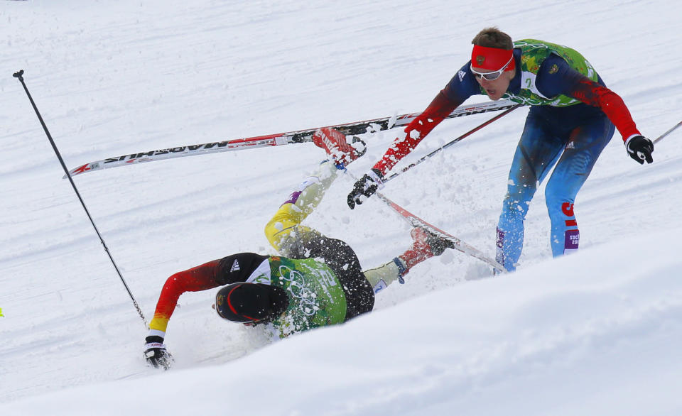 FILE - Germany's Tim Tscharnke falls in front of Russia's Nikita Kriukov, right, after making contact with the skis of Finland's Sami Jauhojaervi in the men's classical-style final of the cross-country team sprint competitions at the 2014 Winter Olympics, Feb. 19, 2014, in Krasnaya Polyana, Russia. Olympic and World Cup race organizers are already used to needing snow-making equipment to create a ribbon of white through the forests as natural snowfall becomes less reliable. Skiers and experts say manmade snow has a higher moisture content, making it ice up quickly.(AP Photo/Dmitry Lovetsky, File)