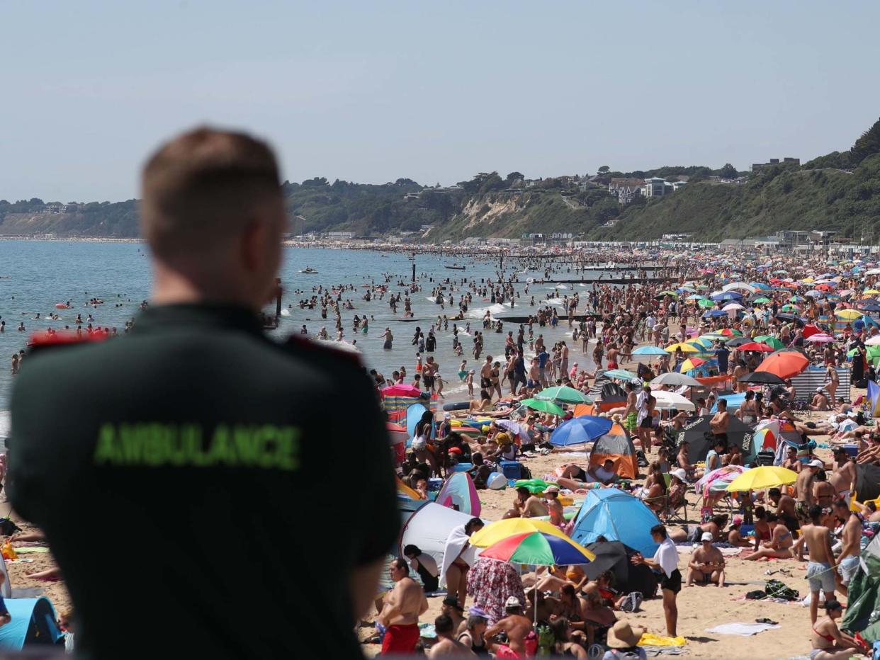 An ambulance worker looks out from Bournemouth Pier as large crowds gather on Bournemouth beach during the heatwave, 25 June 2020: Andrew Matthews/PA