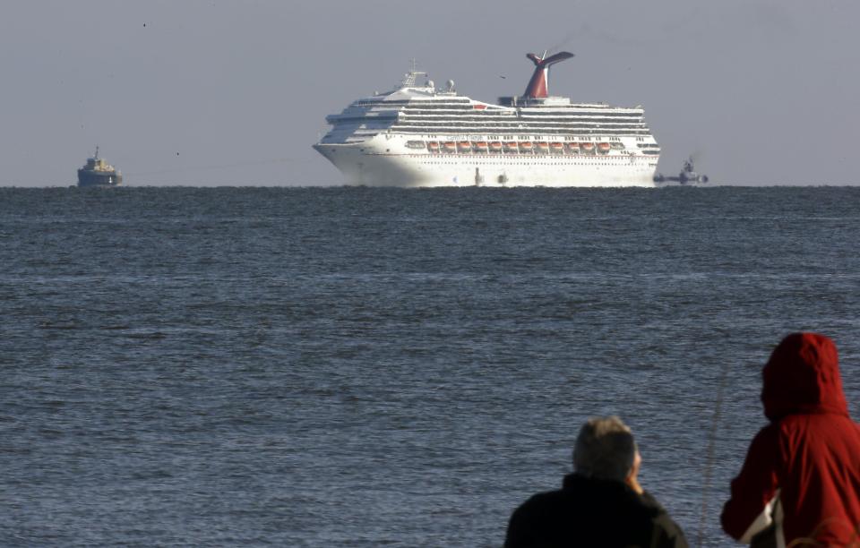 The cruise ship Carnival Triumph is towed towards Mobile Bay near Dauphin Island, Ala., Thursday, Feb. 14, 2013. The ship with over 1,000 passengers aboard has been idled for nearly a week in the Gulf of Mexico following an engine room fire. (AP Photo/Dave Martin)