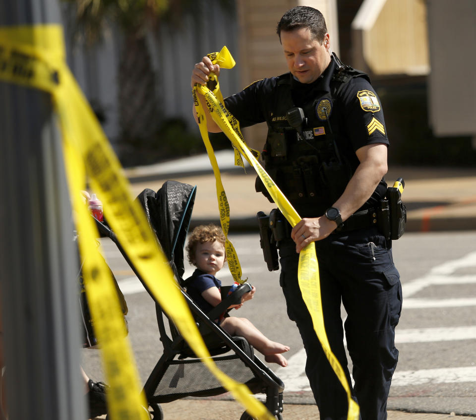 A Virginia Beach police officer takes down police tape along Atlantic Ave. at the Oceanfront on Saturday, March 27, 2021, morning after a fatal shooting the night before in Virginia Beach, Va. A pair of overnight fatal shootings along the beachfront in Virginia Beach wounded several people in a scene described by authorities on Saturday as “very chaotic.” (Stephen Katz/The Virginian-Pilot via AP) /The Virginian-Pilot via AP)