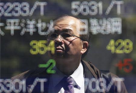 A man is reflected on an electronic stock quotation board outside a brokerage in Tokyo April 14, 2014. REUTERS/Issei Kato
