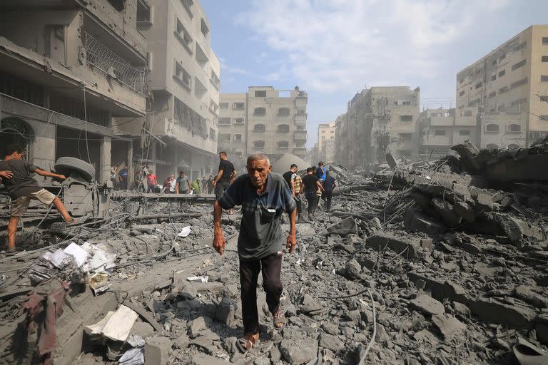 Varias personas caminan entre los escombros luego de un bombardeo