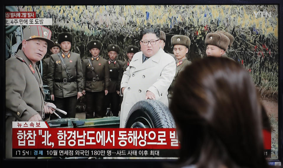 A woman watches a news program reporting North Korea's firing unidentified projectiles with a file image of North Korean leader Kim Jong Un, in Seoul, South Korea, Thursday, Nov. 28, 2019. North Korea on Thursday fired an unidentified projectile, South Korea's military said, three days after the North said its troops conducted artillery drills near its disputed sea boundary with South Korea. (AP Photo/Lee Jin-man)