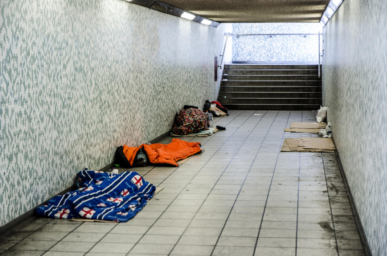 London, England - May 1, 2016: Three homeless people sleeping in sleeping bag in a tunnel with other empty spot marked with cardboards