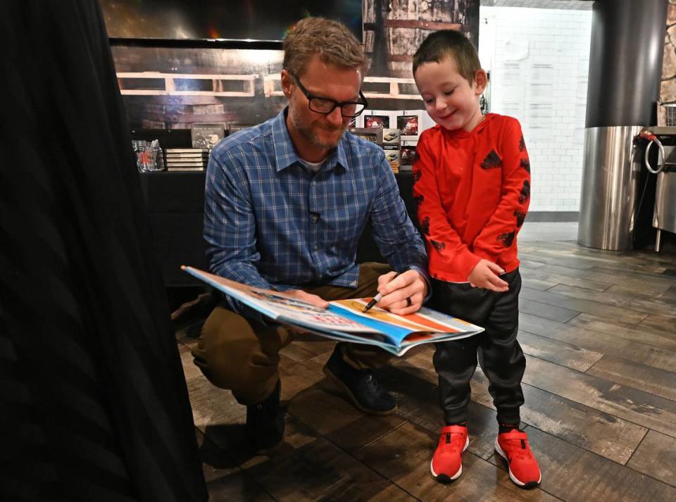 Former NASCAR driver Dale Earnhardt Jr., left, signs an autograph for four-year old Colt Wagner of Dayton, Ohio on Thursday, October 5, 2023 at Earnhardt Jr.’s Whisky River restaurant located at Charlotte Douglas International Airport.