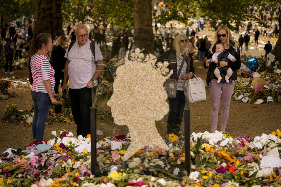 People bring floral tributes to Queen Elizabeth II, the day after her funeral in London's Green Park, Tuesday, Sept. 20, 2022. The Queen, who died aged 96 on Sept. 8, was buried at Windsor alongside her late husband, Prince Philip, who died last year. (AP Photo/Andreea Alexandru)