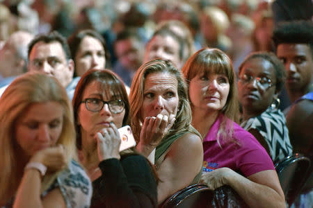 Adults watch a monitor honoring the 17 students and teachers killed at Douglas High School during a CNN town hall meeting, at the BB&T Center, in Sunrise, Florida, U.S. February 21, 2018. REUTERS/Michael Laughlin/Pool