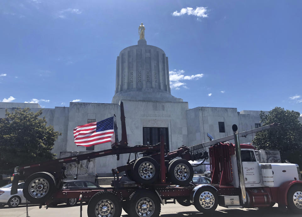 FILE - In this June 12, 2019, file photo, a truck moves around the Oregon state Capitol during a protest against climate bills that truckers say will put them out of business, in Salem, Ore. Oregon is on the precipice of becoming the second state after California to adopt a cap-and-trade program, a market-based approach to lowering the greenhouse gas emissions behind global warming. (AP Photo/Sarah Zimmerman, File)