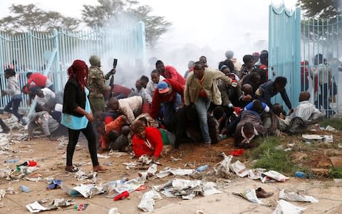 People fall as police fire tear gas to try control a crowd trying to force their way into a stadium to attend the inauguration of President Uhuru Kenyatta at Kasarani Stadium in Nairobi, Kenya November 28 - Credit: BAZ RATNER/ REUTERS