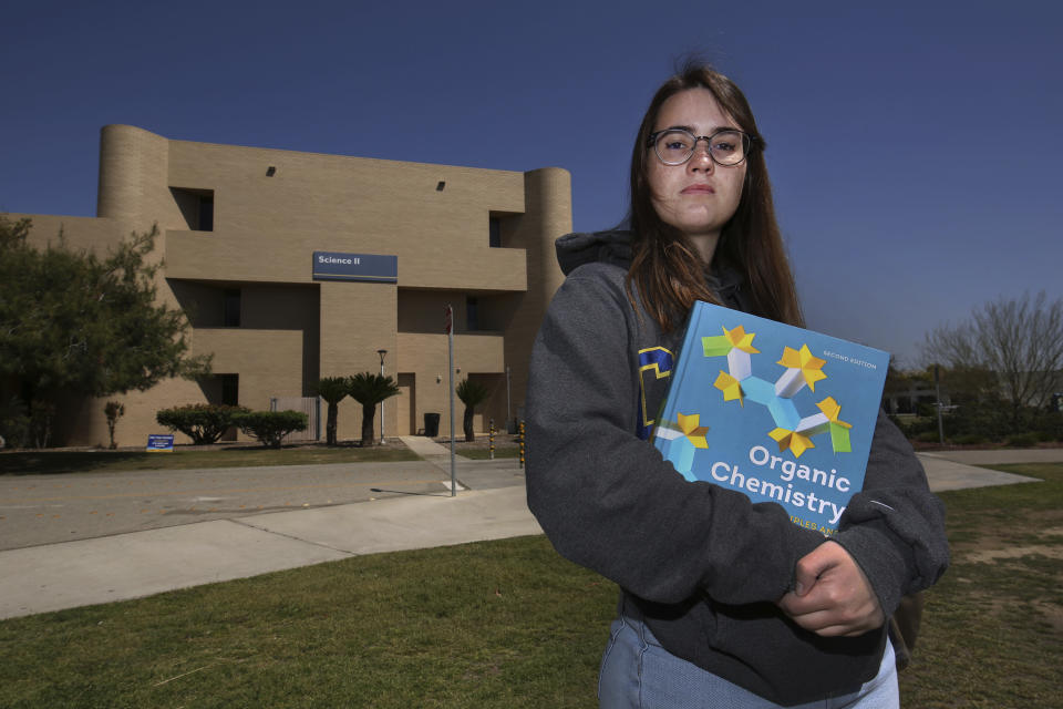 Ricki Korba, 23, stands for a portrait outside her lab at California State University, Bakersfield in Bakersfield, Calif., on Friday, April 14, 2023. The chemistry and music major is retaking classes she already passed once while at a community college. It will add a year to her studies, plus at least $20,000 in tuition and fees. “It just feels like a waste of time. I thought I was supposed to be going to a CSU and starting hard classes and doing a bunch of cool labs.” (AP Photo/Gary Kazanjian)