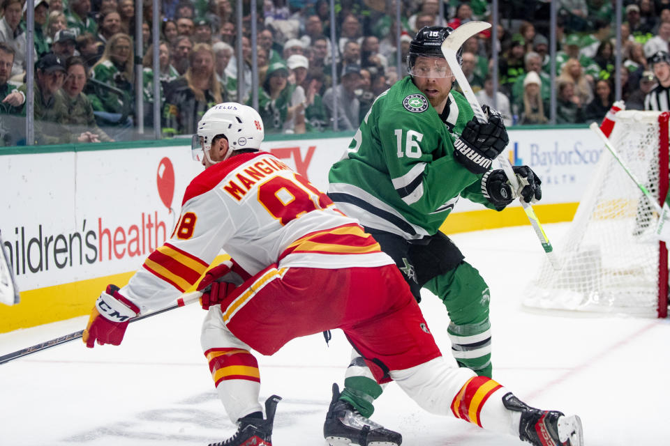 Calgary Flames left wing Andrew Mangiapane (88) gets the puck away from Dallas Stars center Joe Pavelski (16) during the second period of an NHL hockey game, Friday, Nov. 24, 2023, in Dallas. (AP Photo/Emil T. Lippe)