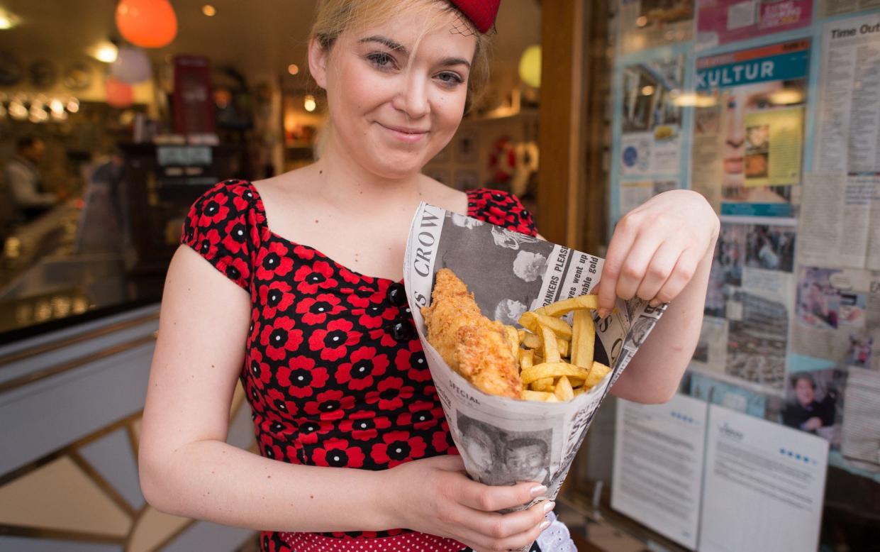 A person poses with fish and chips at Poppies fish and chip restaurant in east London