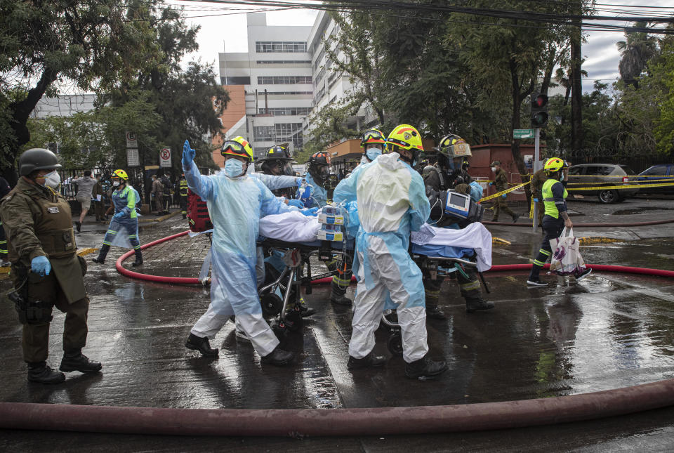Trabajadores de salud ayudan a evacuar a un paciente con COVID-19 luego de un incendio en el hospital San Borja en Santiago de Chile, el sábado 30 de enero de 2021. (AP Foto/Esteban Félix)